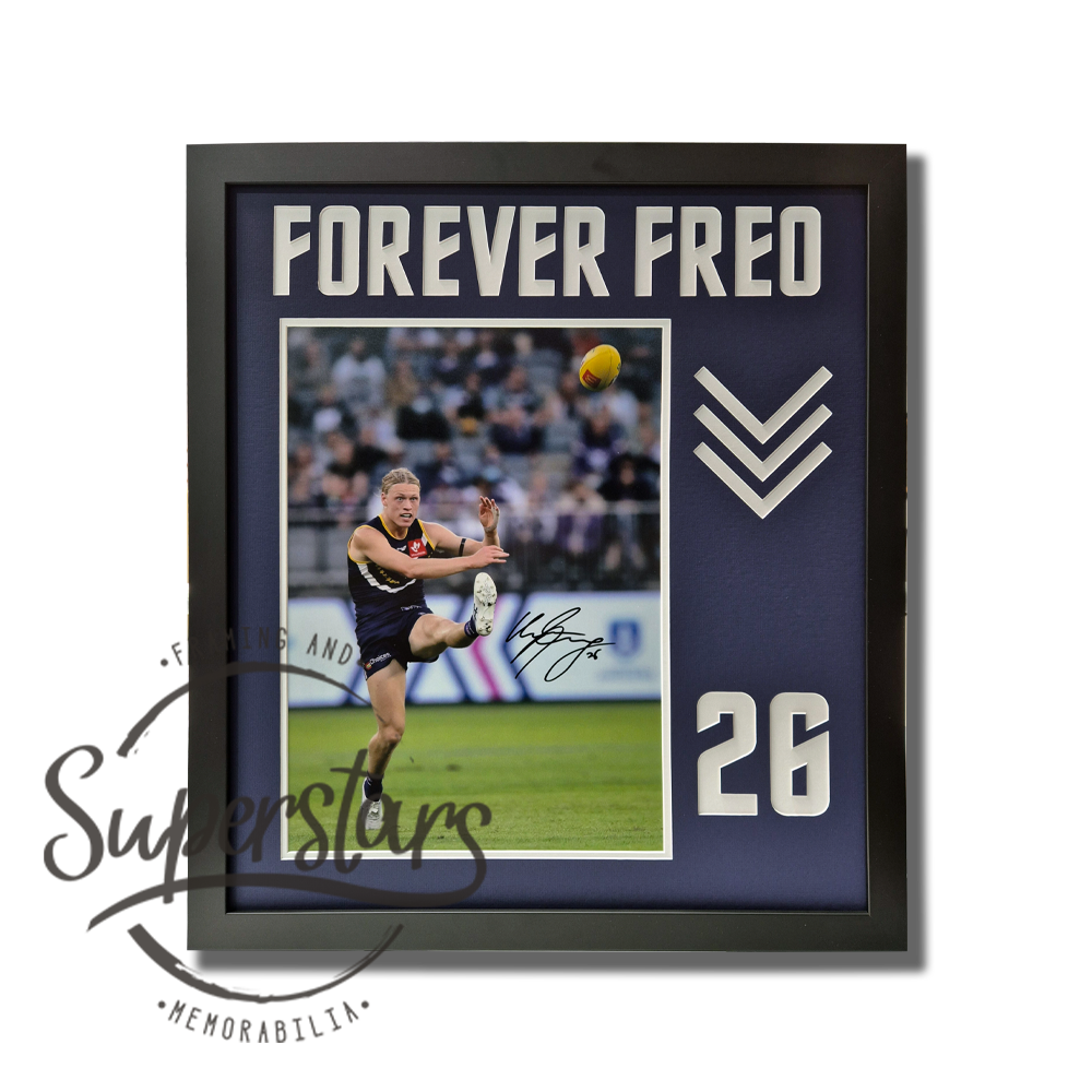 A large photo of Hayden Young during a game. The photo is surrounded by a thin white border, and a larger dark purple border. The dark purple border has the words Forever Freo cut into it across the top, the Freo dockers arrows and Caleb's jumber number 26.