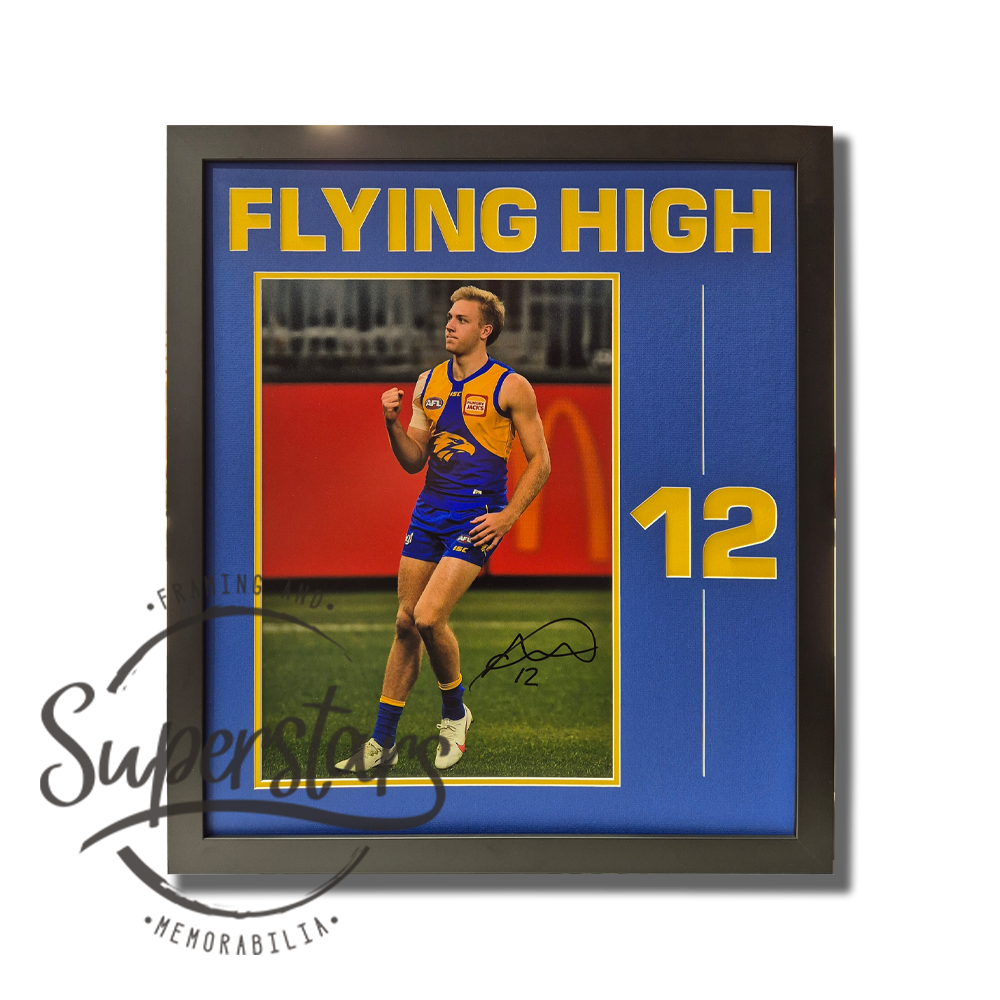 Oscar Allen Memorabilia. To the left is a large close up photo of Oscar celebrating kicking a goal this photo is surrounded by a thin yellow border. Alongside the photo is the number 12 cut into the matting so it is also yellow. The words Flying High are cut into the top as a title. The main border is royal blue.